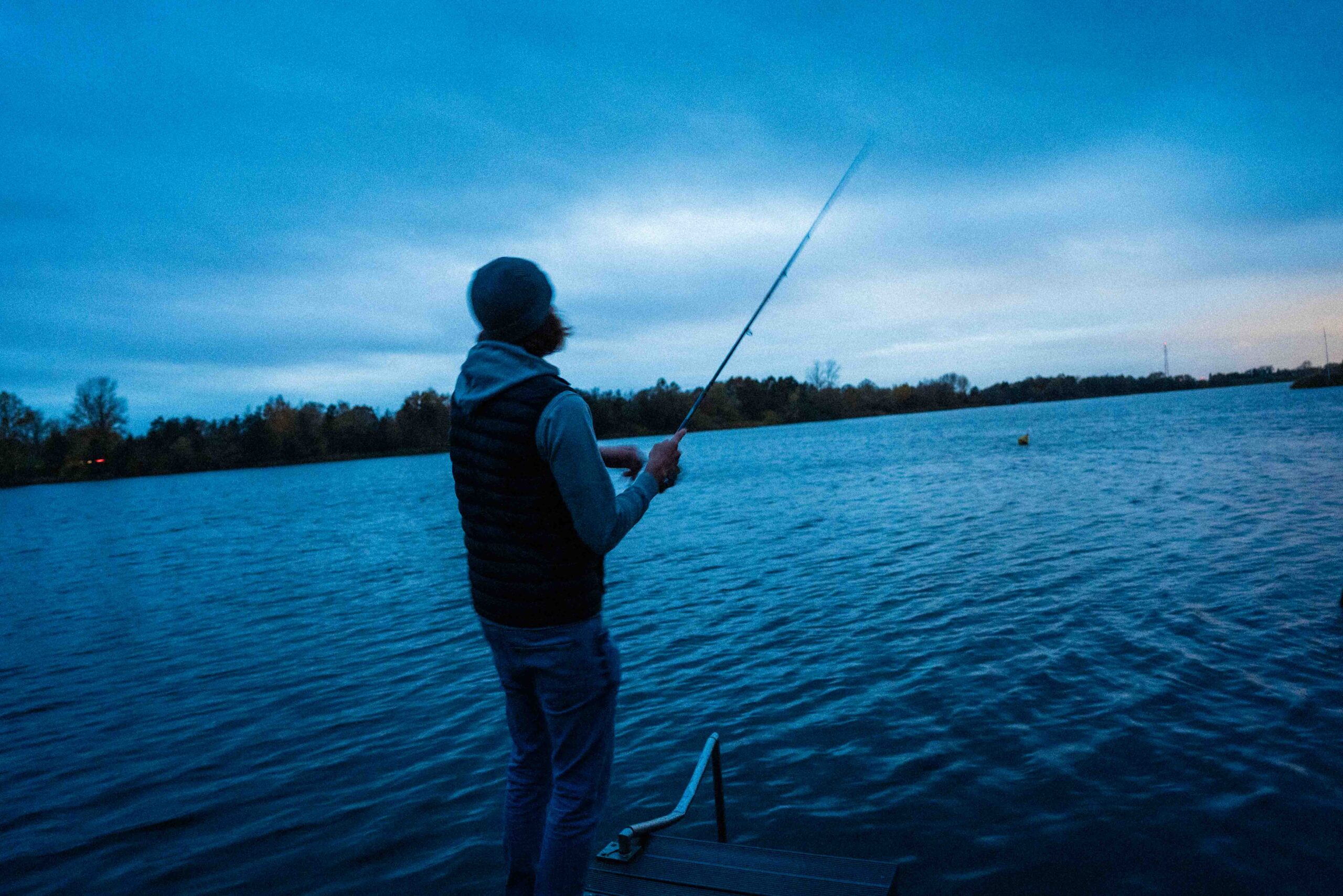 Angler am See in Abendstimmung mit Angelrute - fishingLads Outdoor-Abenteuer
